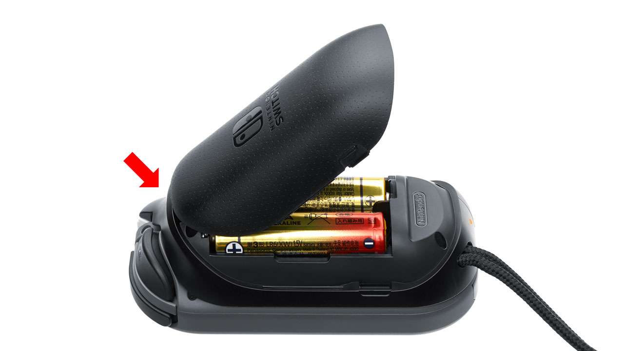 Insert the AA batteries into the battery compartment, using the + and − marks to ensure correct alignment. Then, insert the clip on the upper part of the battery cover into the hollow cavity in the Joy-Con AA battery pack.